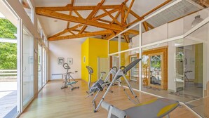 Une salle de sport équipée de matériel d’exercice, dotée de grandes fenêtres et d’un plafond en bois.