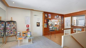 A reception area with a wooden reception desk, a bulletin board with various notices, and a glass display case with brochures. - Studio sur les Rives de l'Ardèche (VALLON-PONT-D’ARC)