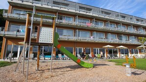 A multi-story building with balconies, outdoor seating, and a playground. - Appartement moderne au calme ! (Roz-Sur-Couesnon)