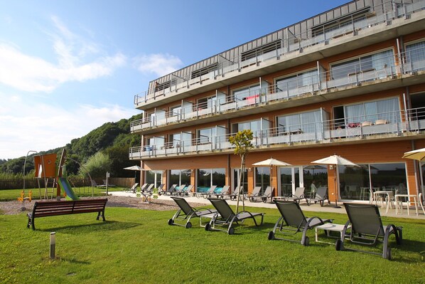 A multi-story hotel with outdoor seating and a playground.