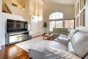 Ein großzügiges Wohnzimmer mit einem großen Flachbildfernseher, einem Ecksofa und einer Treppe, die in ein Obergeschoss führt.