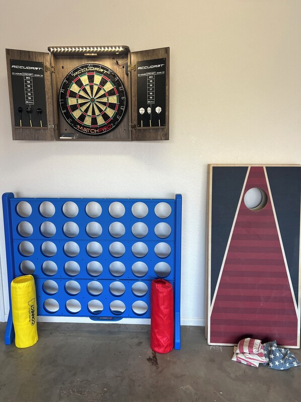 Eine Dartscheibe, eine blaue Flippermaschine und eine große dreieckige Spielplatte mit einer Öffnung in der Mitte.