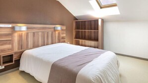 A bedroom with a sloped ceiling, a skylight, a bed with a headboard, and built-in shelving. - Près des Remontées ! Appart confortable +Parking (Gresse en Vercors)