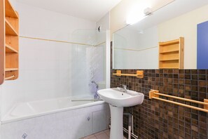 Ein Badezimmer mit Badewanne, Waschbecken, Spiegel und Duschkabine.