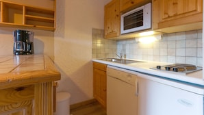 A compact kitchen with wooden cabinets, a microwave, a dishwasher, and a coffee maker.