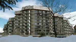 A multi-story building with balconies, surrounded by snow.