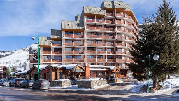 A multi-story hotel with balconies, a ski lodge, and a parking area.