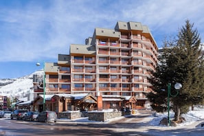 Un hotel de varios pisos con balcones, un albergue de esquí y un área de estacionamiento.