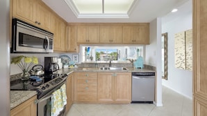 Una cocina moderna con armarios de madera, un microondas de acero inoxidable, cafetera y lavavajillas.