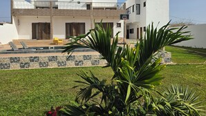 Une maison moderne à deux étages, dotée d’une piscine, d’un terrain de basketball et d’une pelouse bien entretenue.