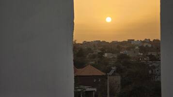 A sunset view from a balcony with a cityscape in the background.