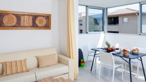 Un salon moderne avec un canapé, une table basse et un coin repas comprenant des chaises et une table mise pour le petit-déjeuner.