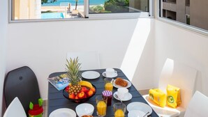 Un balcon avec une table préparée pour le petit-déjeuner, donnant sur une plage et l’océan.