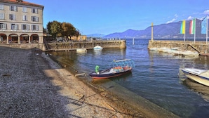 Vista de un frente marítimo con un edificio, barcos y banderas.
