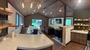 Una cucina moderna con parete in pietra, soffitto in legno e un'isola grande.