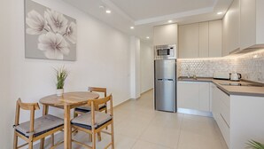 A modern kitchen with a built-in microwave, stainless steel refrigerator, and a small island with a toaster.