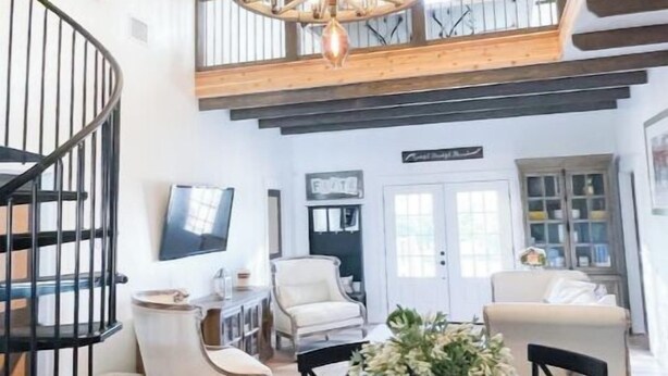 A spacious dining area with a high ceiling and exposed wooden beams. There is a round table with chairs and a chandelier above. - Texas Ambience at the Barn and Silo
 (Liberty Hill)