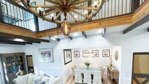 A spacious living area with a high ceiling, a dining table with chairs, a sofa, and a chandelier. - Texas Ambience at the Barn and Silo
 (Liberty Hill)