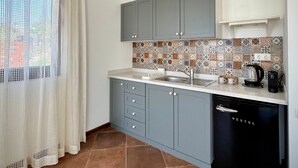 A modern kitchen with grey cabinets, a tiled backsplash, and a black dishwasher. - Casa Caria Suites (Bodrum)