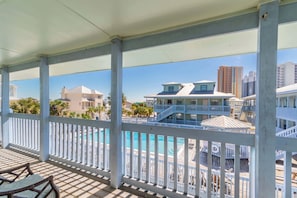 Un balcon fermé offrant une vue sur une piscine et des bâtiments.