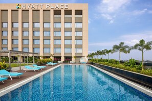 Ein Swimmingpool mit Liegestühlen und ein Gebäude im Hintergrund, auf dem "HYATT PLACE" steht.