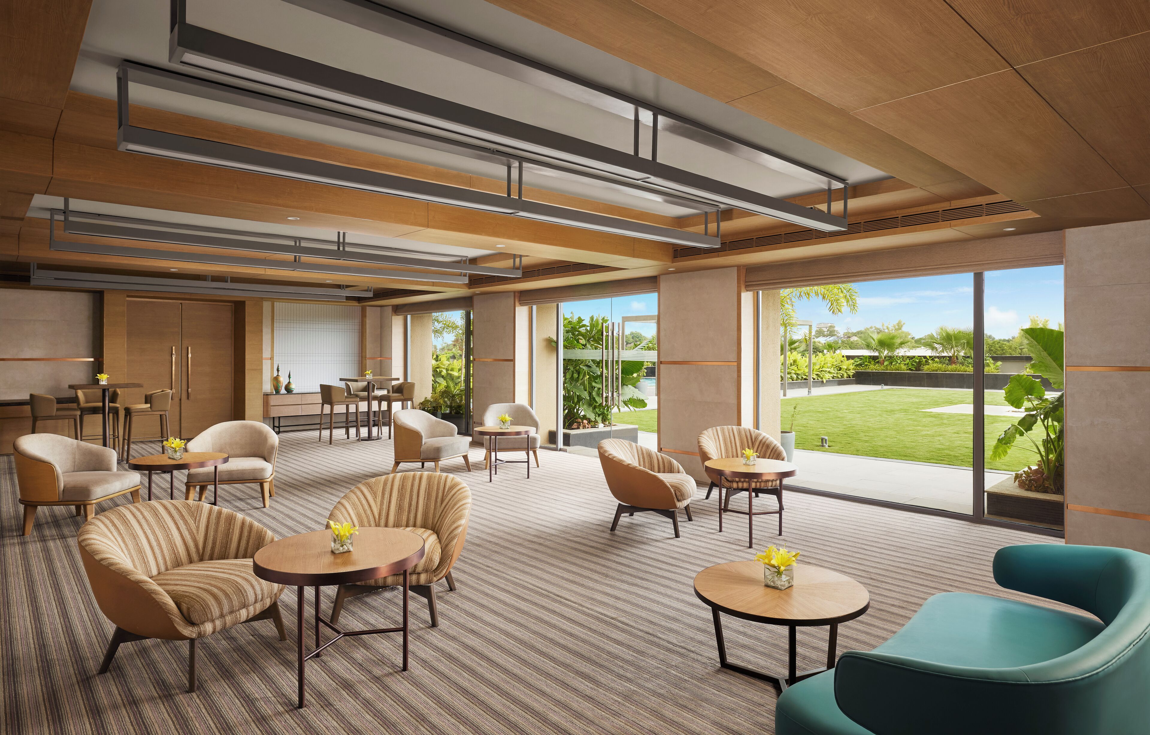 A modern hotel lobby with comfortable seating, large windows, and a view of the outdoors.