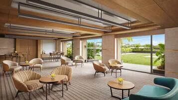 A modern hotel lobby with comfortable seating, large windows, and a view of the outdoors.