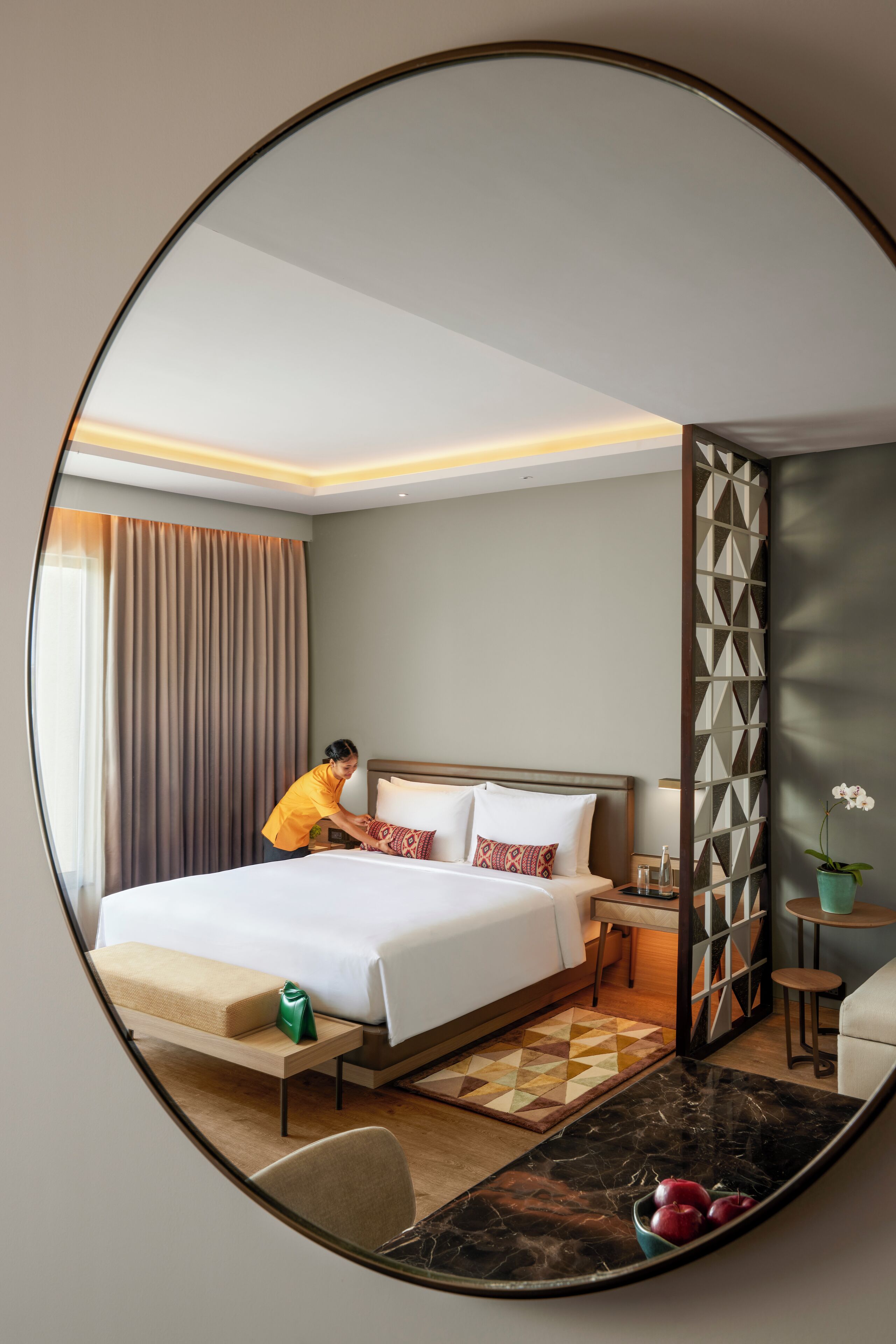 A hotel room with a bed, bedside table, lamp, and a decorative wall panel.