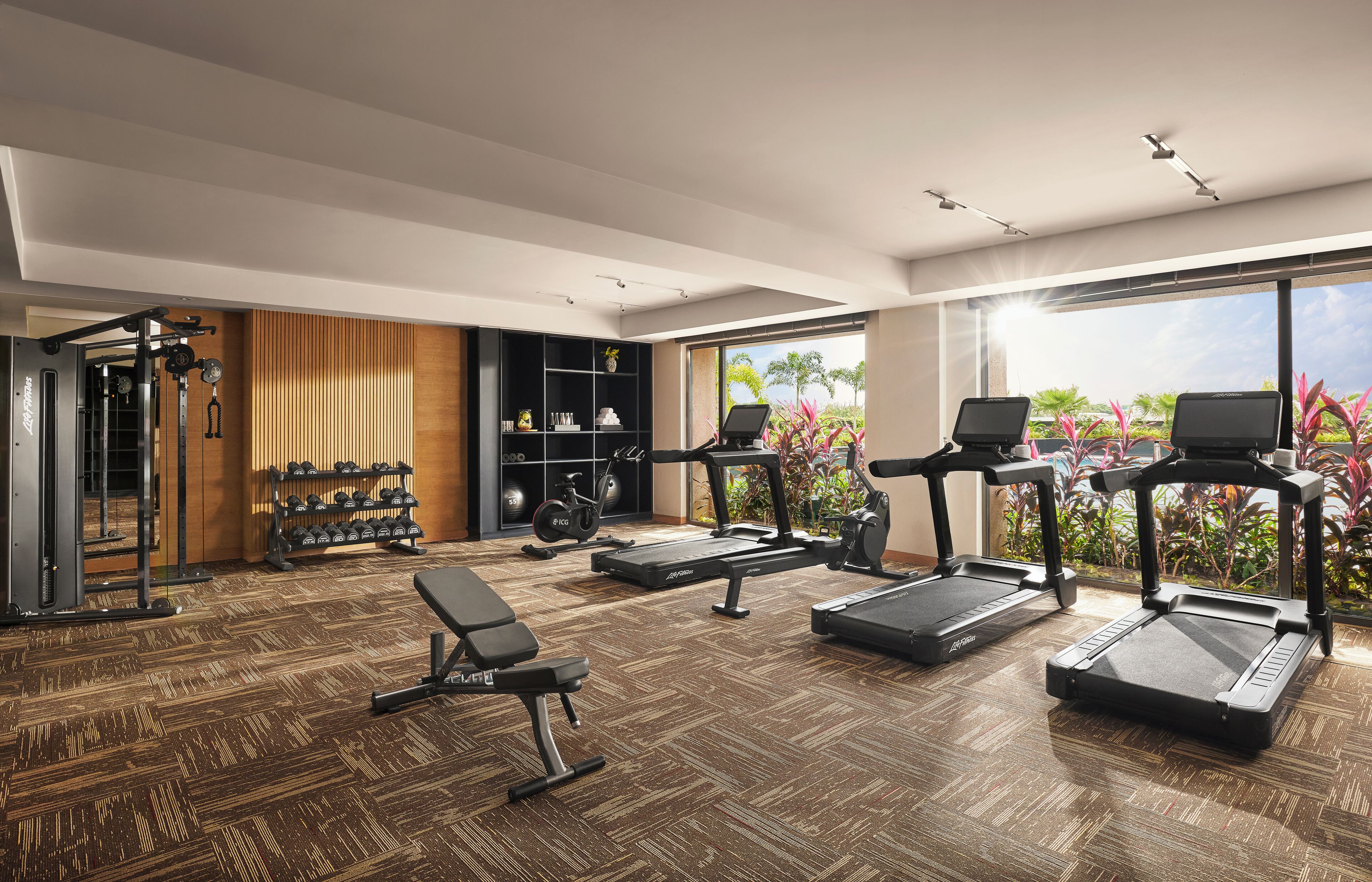 Une salle de sport moderne pour la maison, équipée de tapis de course, d’haltères et d’un banc.