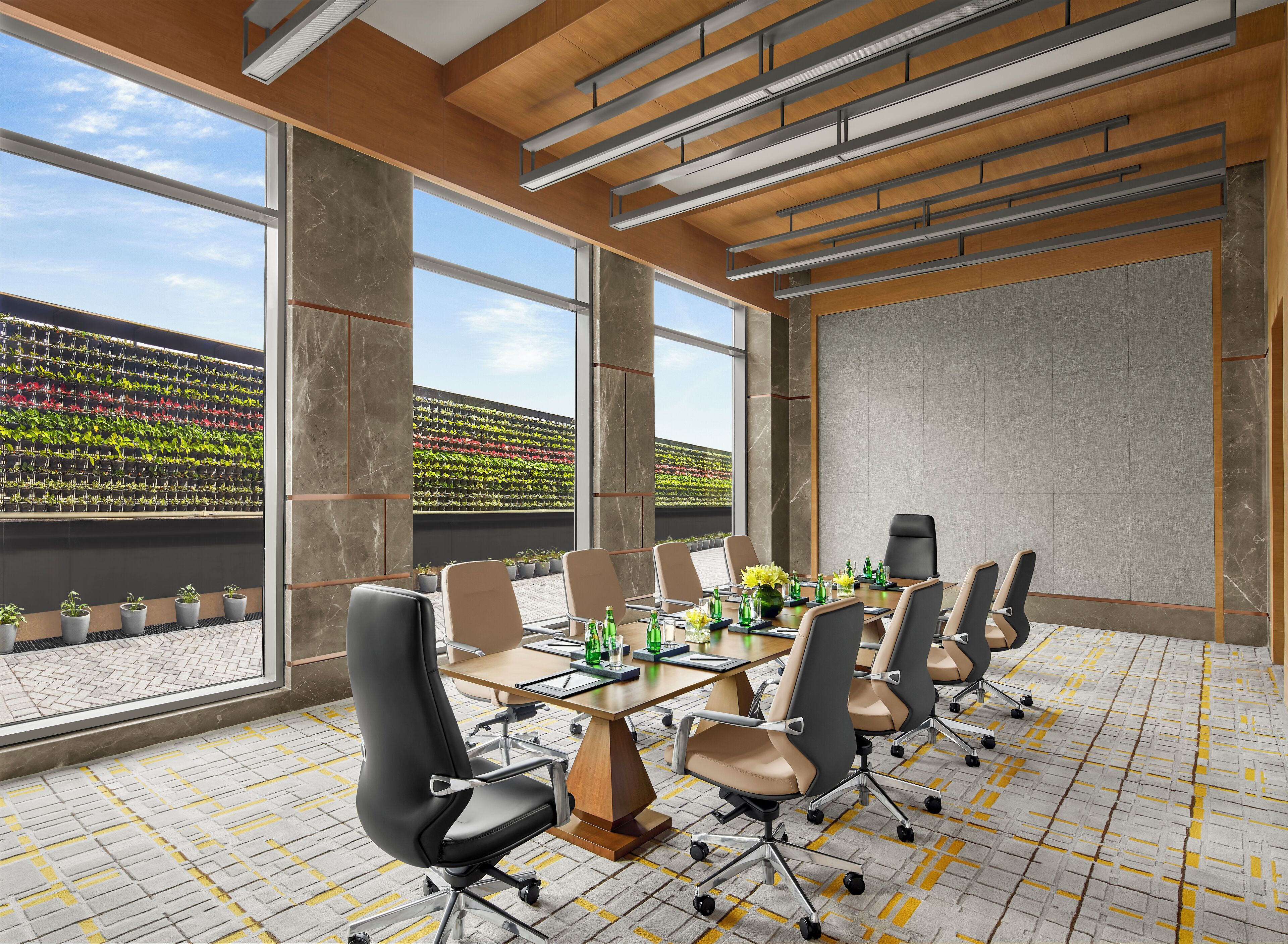 Een moderne vergaderzaal met een grote tafel, meerdere stoelen en uitzicht op een dakmoestuin door grote ramen.