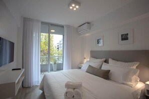 A modern hotel room with a large bed, a flat-screen TV, a balcony with curtains, and a ceiling-mounted air conditioner. - BAIRES HOMES PALERMO III (Buenos Aires)