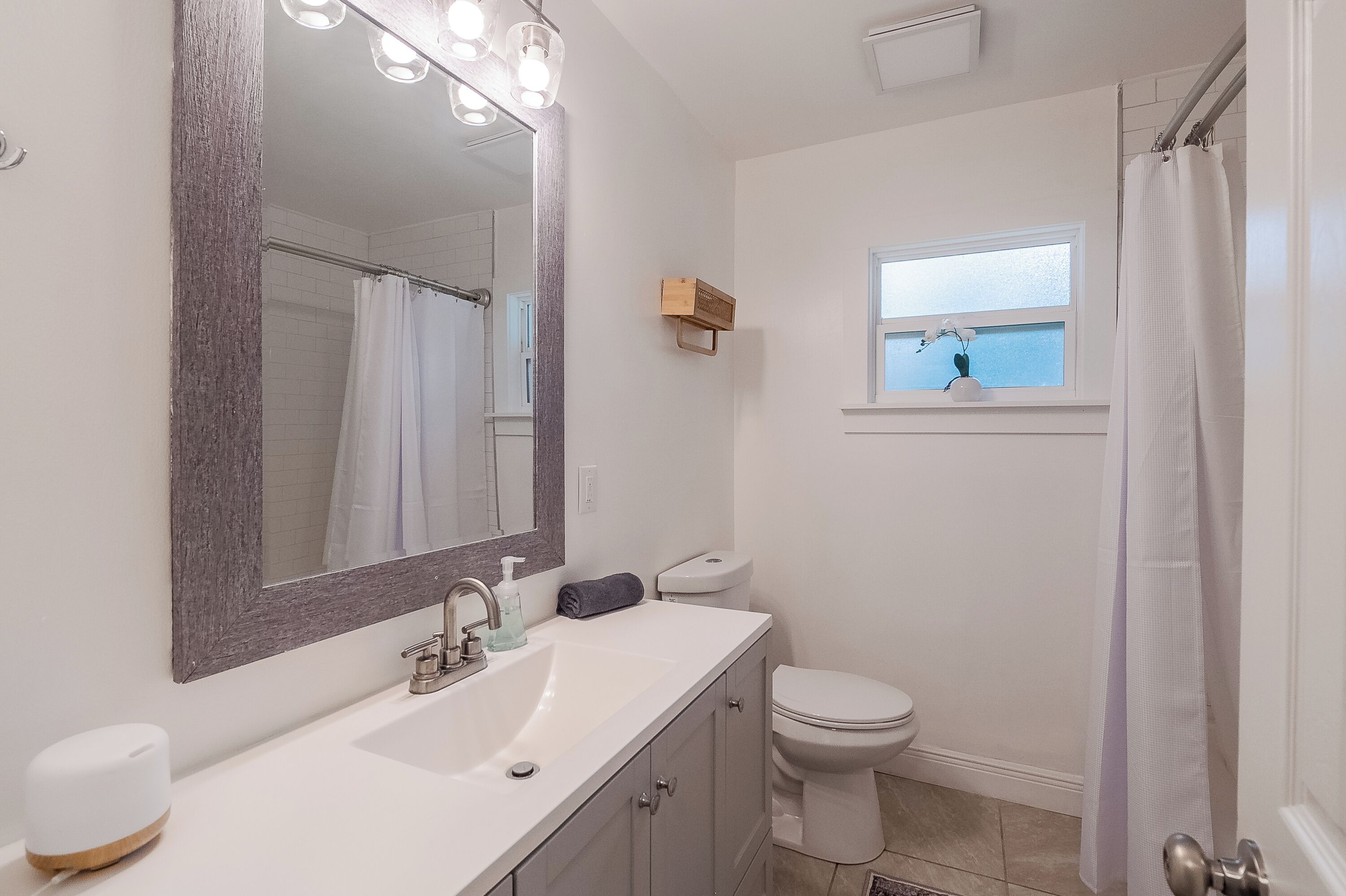 A bathroom with a large mirror, a sink, a toilet, and a window with a view.
