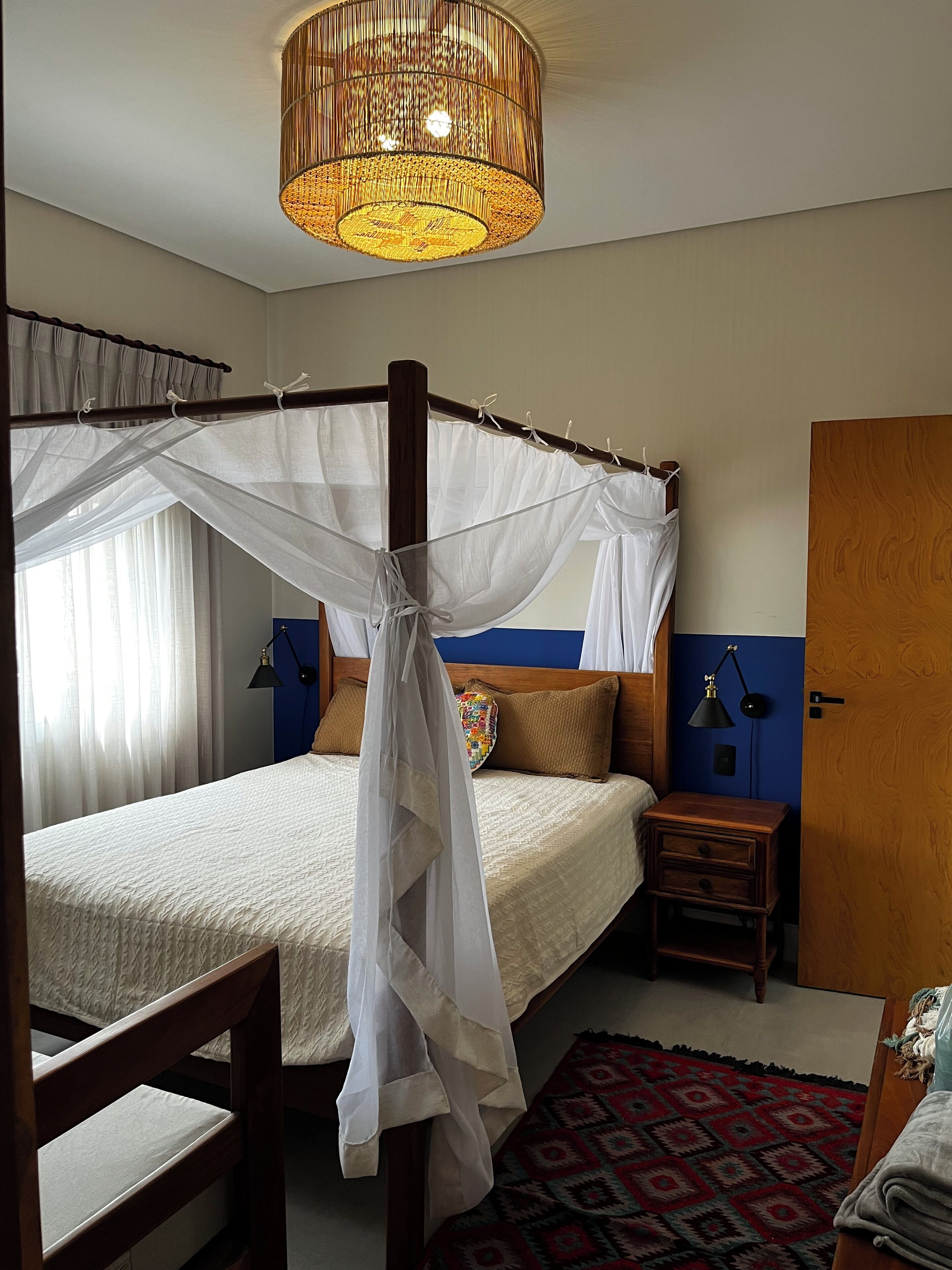 Une chambre à coucher avec un lit à baldaquin, un dais, une table de chevet avec une lampe et un tapis à motifs.