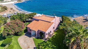 Una propietat a la costa amb una casa de teules terracota, un vial pavimentat i un jardí ben cuidat.