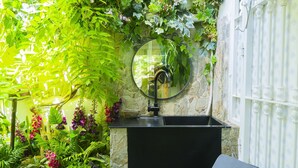 A black sink with a mirror above it, surrounded by lush greenery and plants. - Cubo’s Poseidon Suites 3 & Pool for Adults / room / air conditioning / community pool / free wifi (Benalmádena)
