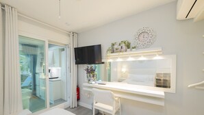 A modern hotel room with a large bed, a vanity with a mirror, a flat-screen TV, and a small desk area. - Cubo’s Poseidon Suites 3 & Pool for Adults / room / air conditioning / community pool / free wifi (Benalmádena)