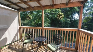 Une terrasse en bois dotée d’un espace abrité, de deux chaises et d’une table.
