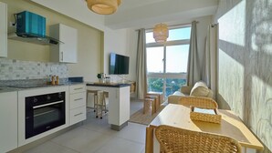 Cocina moderna con horno empotrado, comedor con sillas de mimbre y un amplio ventanal con vistas.