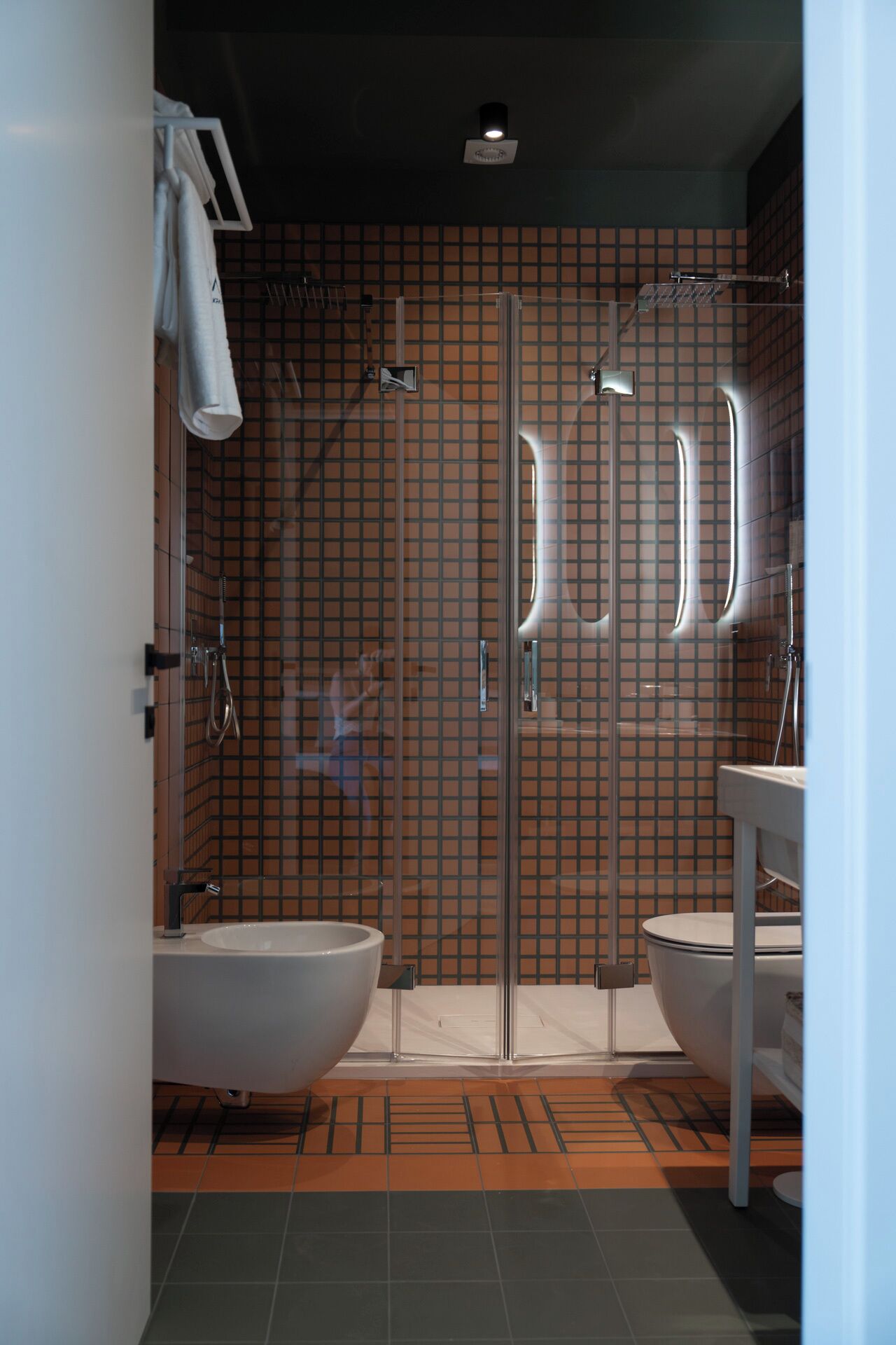 A bathroom with two sinks, a glass shower enclosure, and a tiled floor.