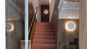 A staircase with a wooden finish, a glass door on the left, and a wall-mounted shelf with potted plants. - Leluan Bed & Breakfast (Mola di Bari)