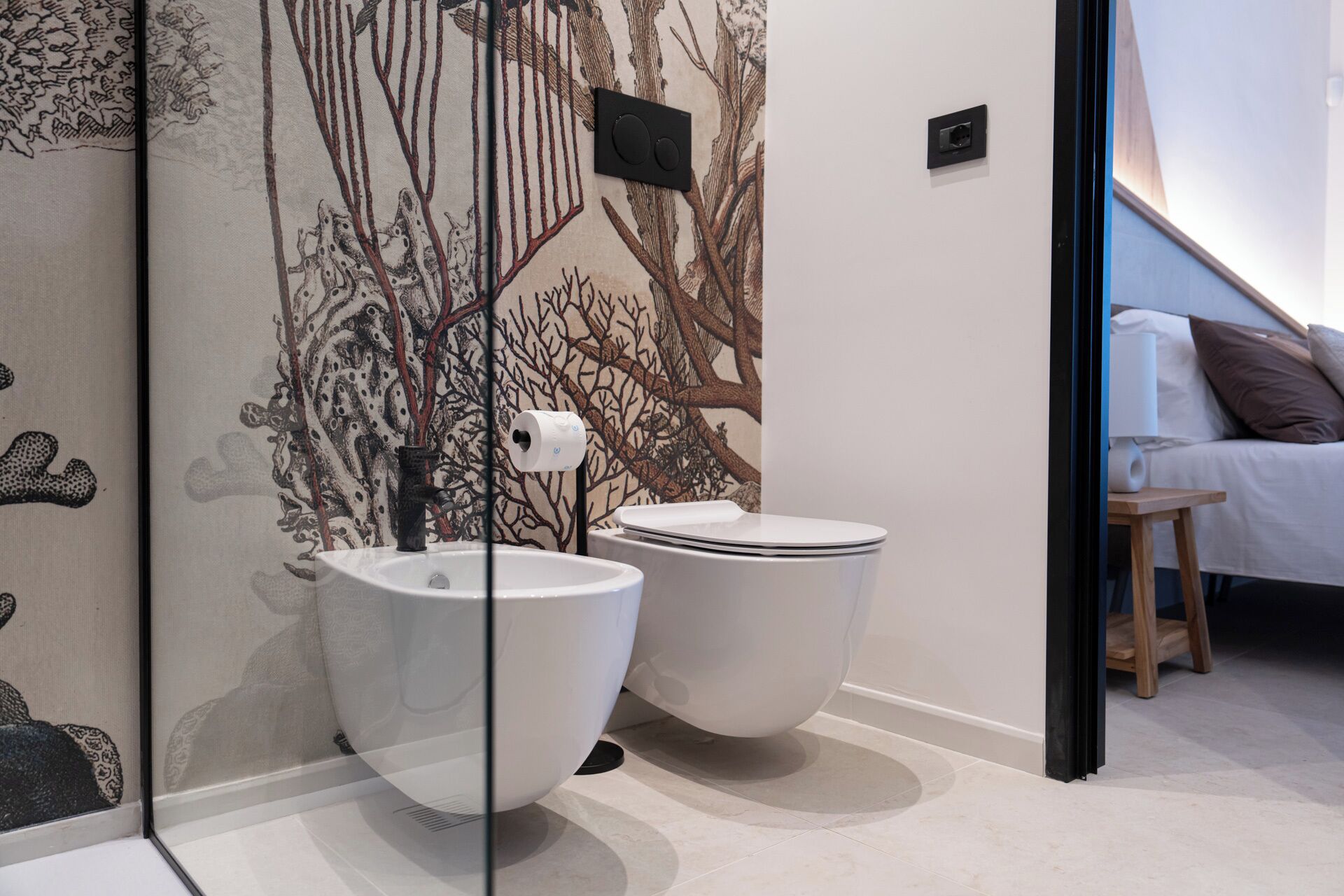 Ein modernes Badezimmer mit einem einzigartigen Wanddesign im Baummotiv, einer Toilette und einem Bidet.