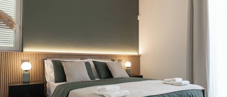 A modern bedroom with a bed, bedside lamps, and a window with curtains.