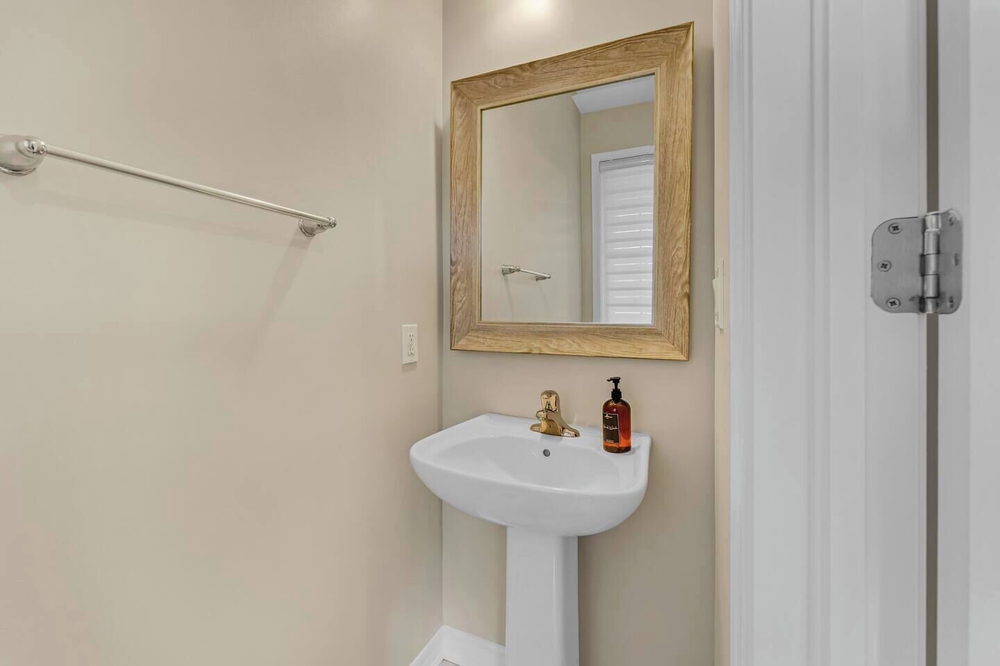 This minimalist powder room offers a clean and fresh ambiance with its soft neutral tones and sleek pedestal sink. Perfect for quick refreshes, it adds a touch of simplicity and elegance to your stay.