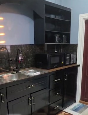 Une cuisine moderne avec des meubles de rangement aux couleurs sombres, un four à micro-ondes encastré et un évier.