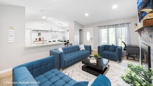 Uma sala de estar moderna com sofás azuis, uma mesa de centro preta e uma lareira.