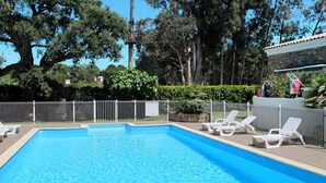 Piscina con sillones de descanso blancos y un área cercada.
