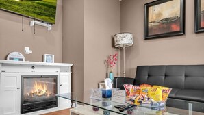 Un soggiorno con camino, un divano, un tavolino da caffè con snack e una TV a parete.