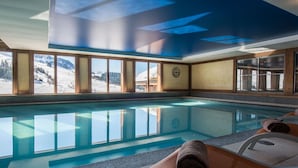 Un espace piscine offrant une vue dégagée sur un paysage enneigé, avec des murs en bois et une horloge au mur.