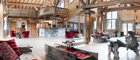 A spacious interior with wooden beams, a stone fireplace, and red furniture.