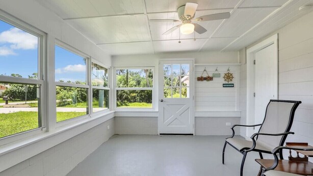A room with large windows, a ceiling fan, and a door leading outside. - Kayaks & Access to Beach on Matlacha Pass (Saint James City)
